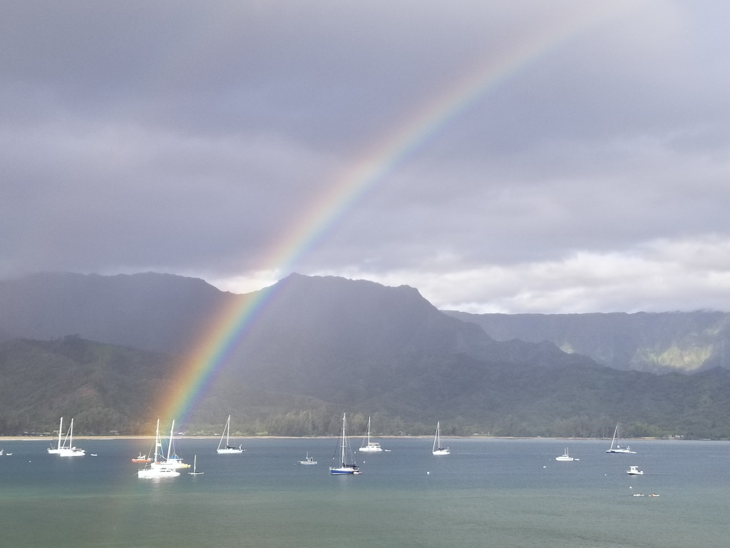 A rainbow touching down on sail boats bobbing in Hanalei Bay, Kauai